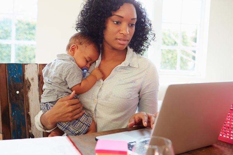 Parent juggling kid and work on computer